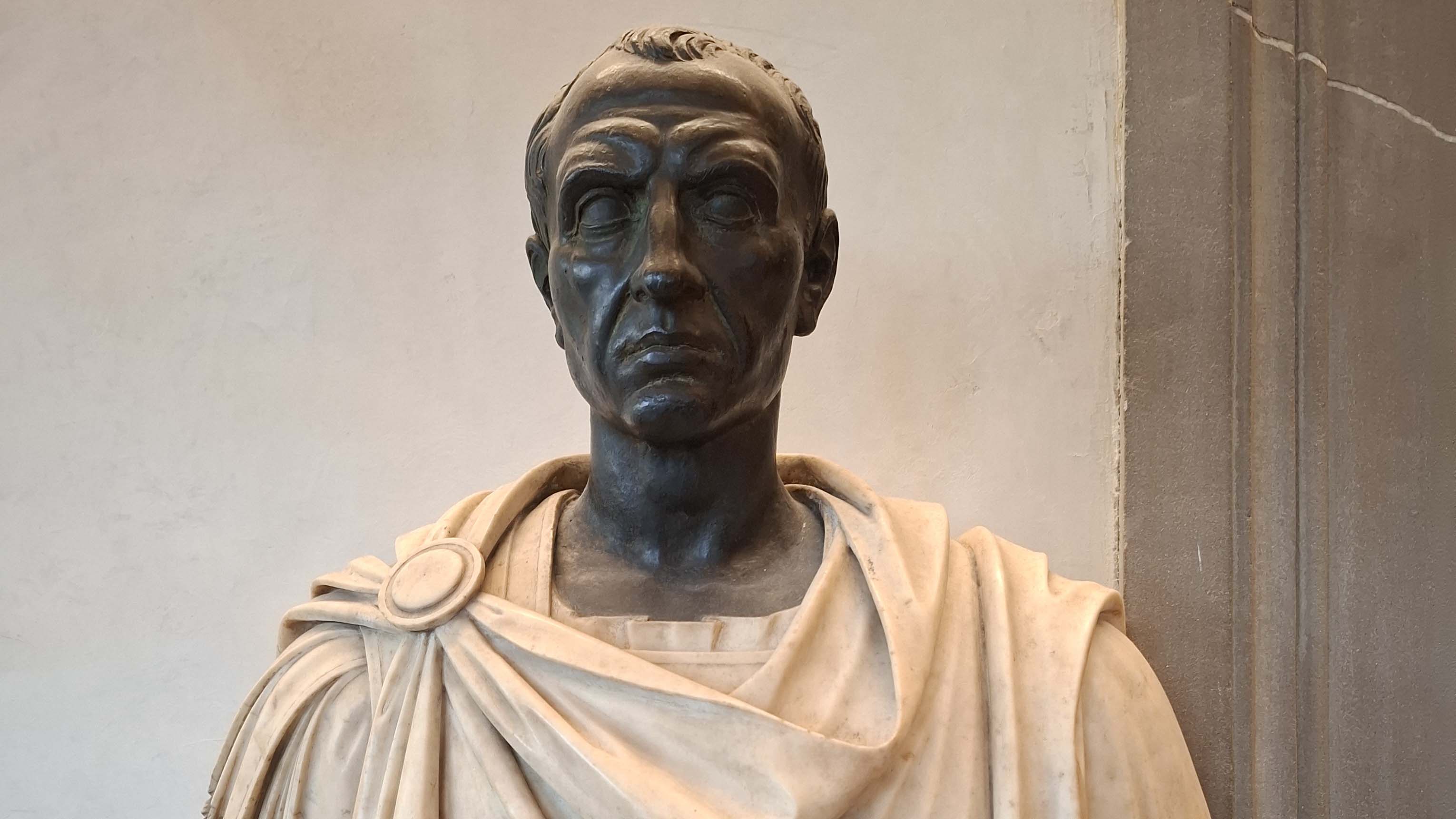 Bilden visar en staty av en man med mantel.