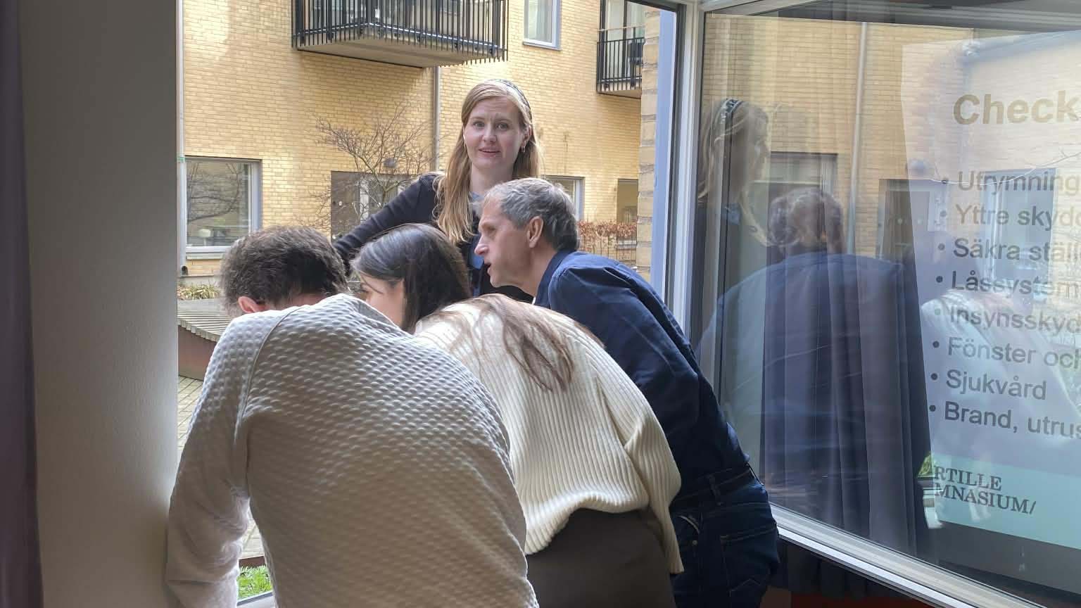 Bilden visar personal som kollar utrymningsväg genom fönster.